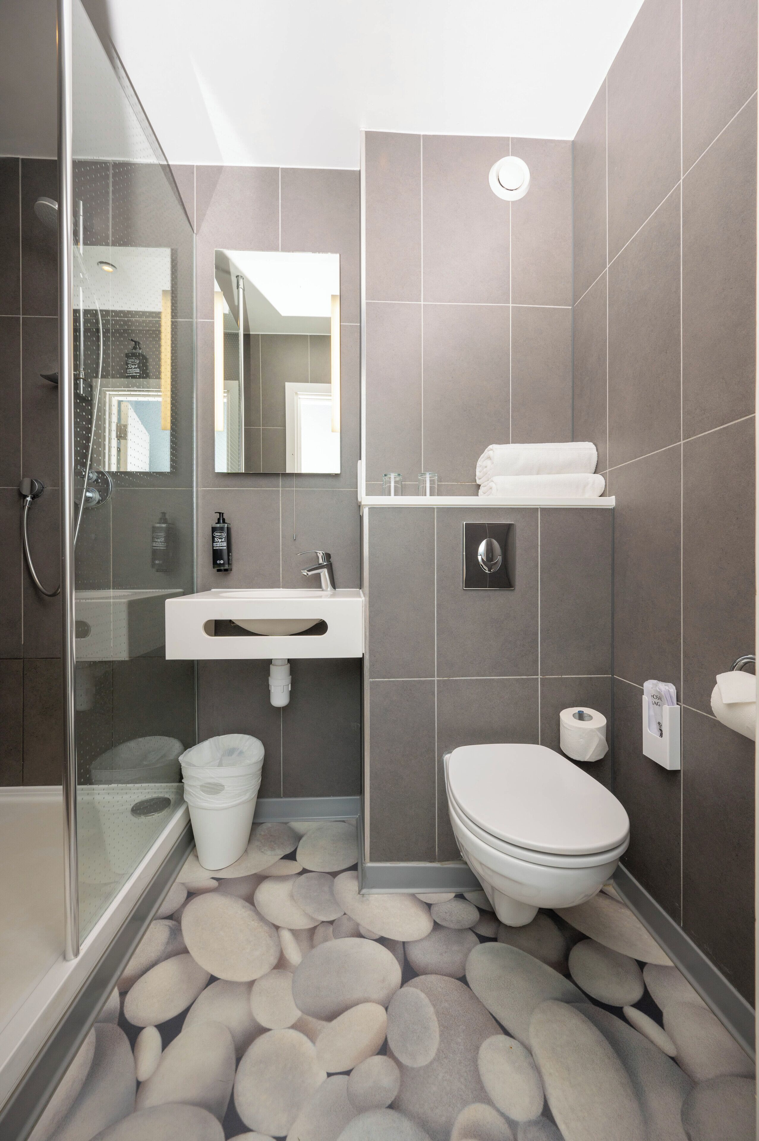A modern bathroom with a glass shower enclosure, a white sink, and a toilet.