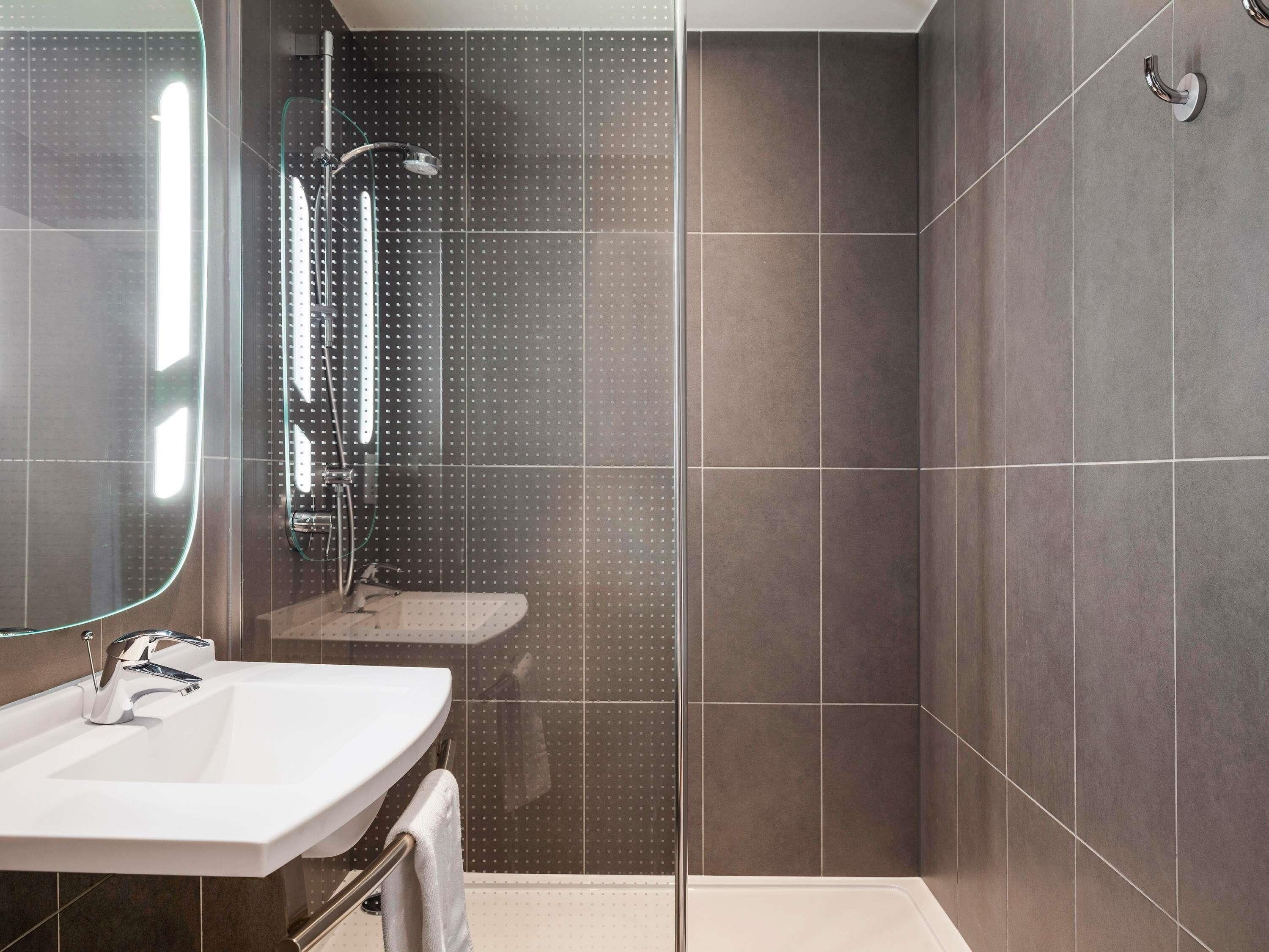 Une salle de bain moderne avec une douche, un lavabo et un miroir.