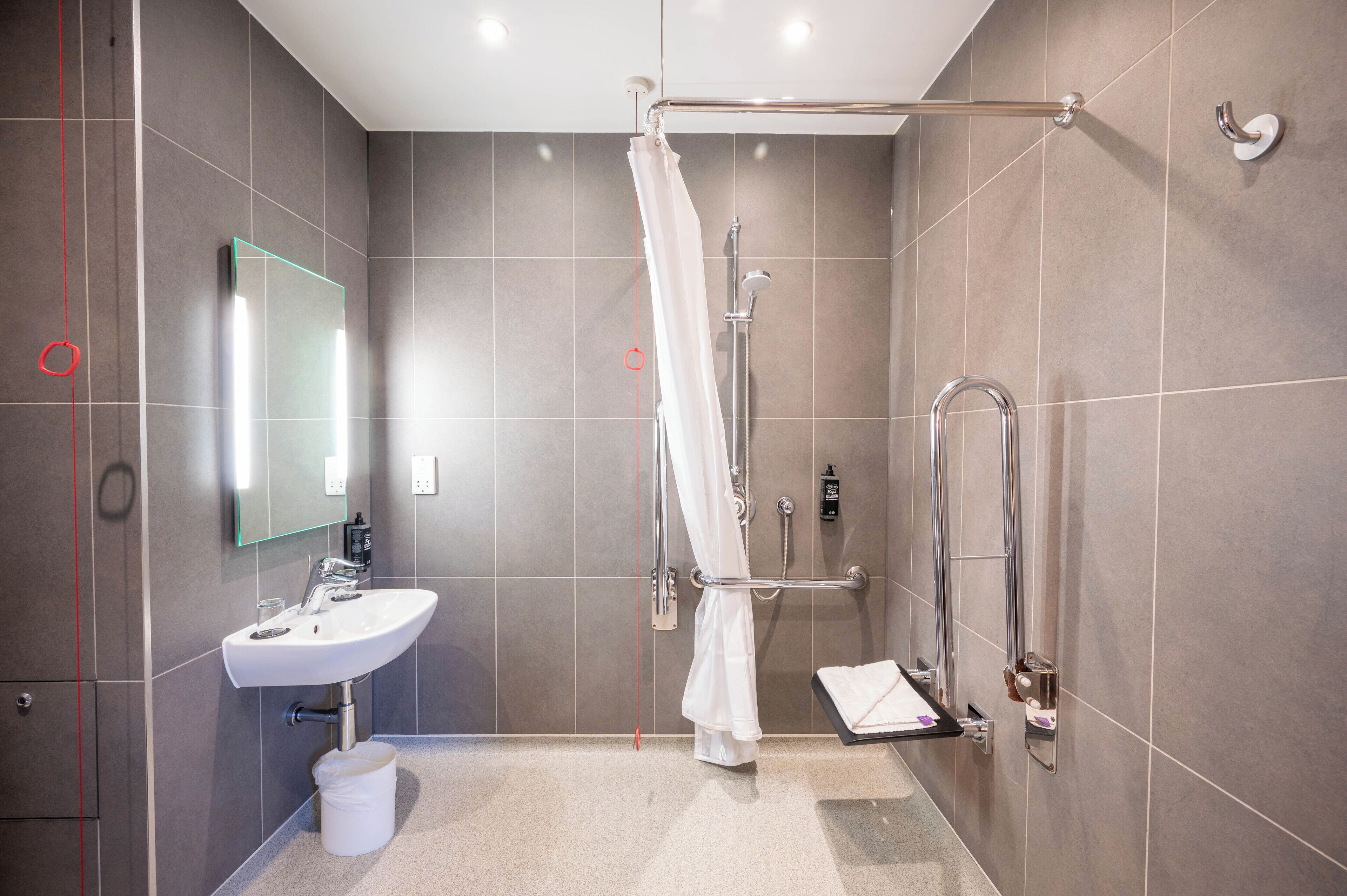 Un baño moderno con ducha, lavabo y espejo.