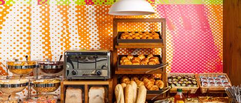 Ein reichhaltiges Buffet mit verschiedenen Speisen, einem Toaster und einer Brodauswahl.