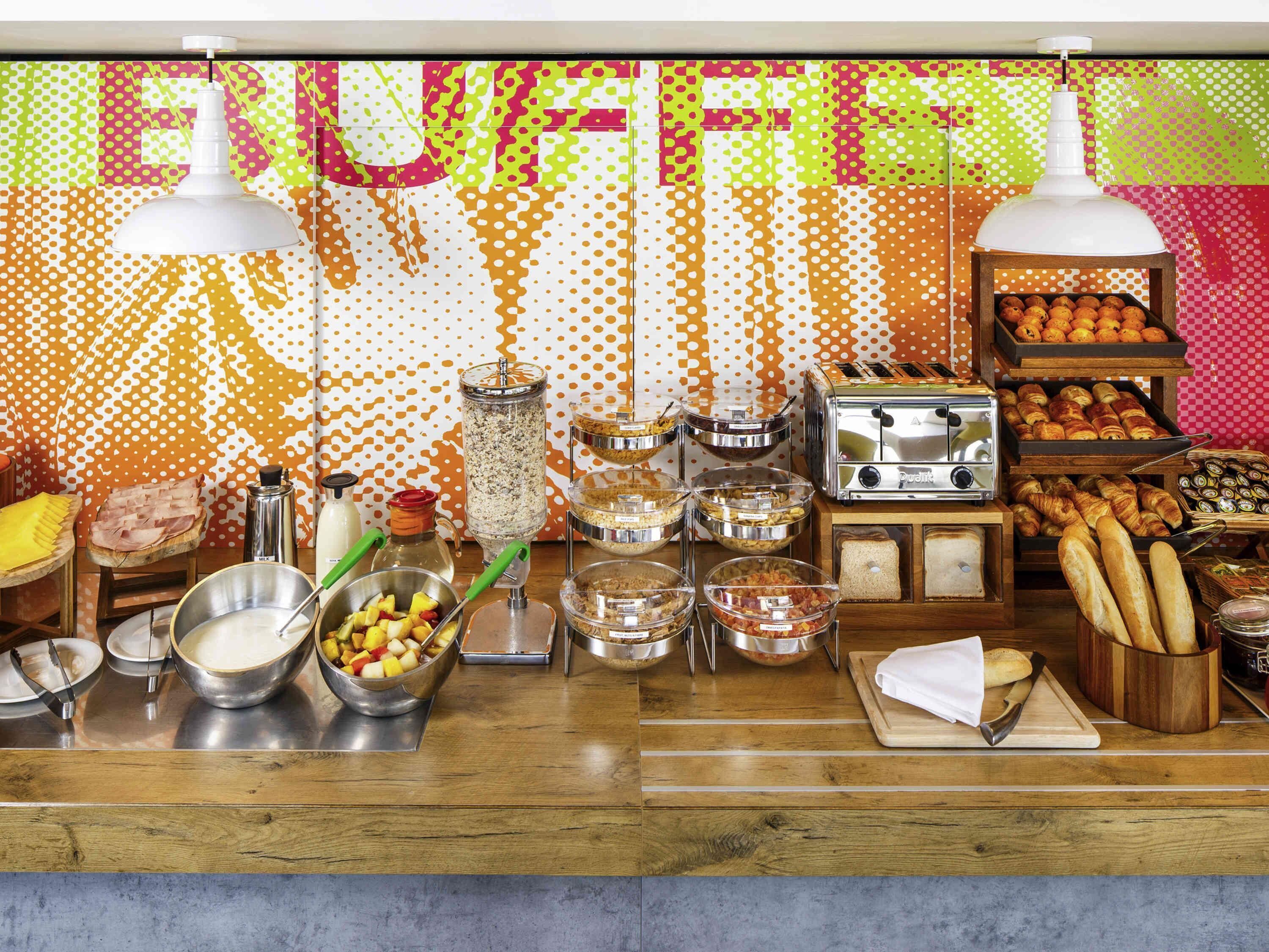 A buffet setup with various food items, a toaster, and a wooden counter.