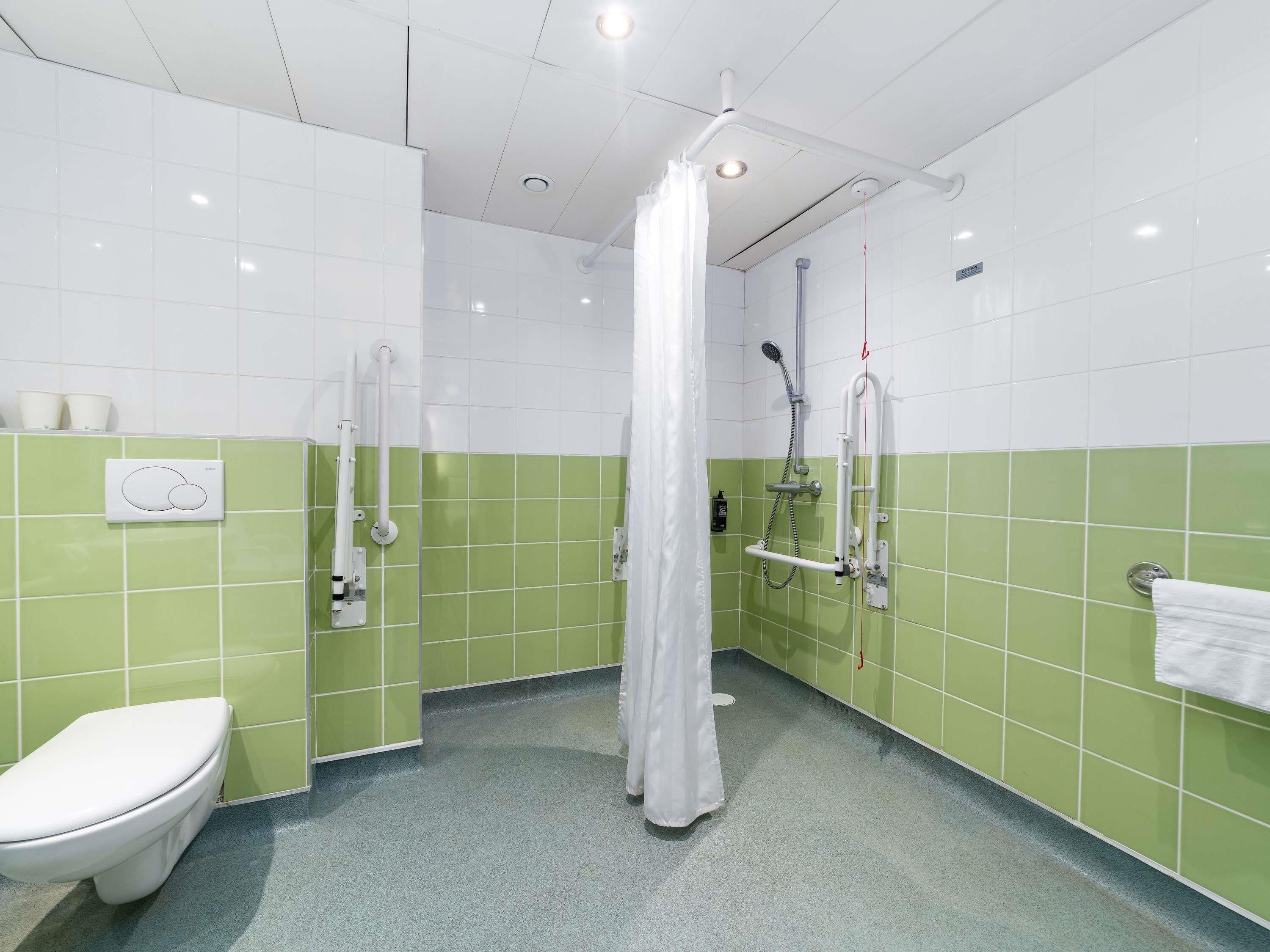 Un baño con inodoro, ducha con cortina y toallero.