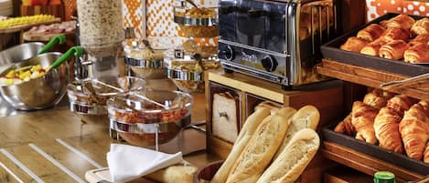 A buffet setup with various food items, a toaster, and condiments.