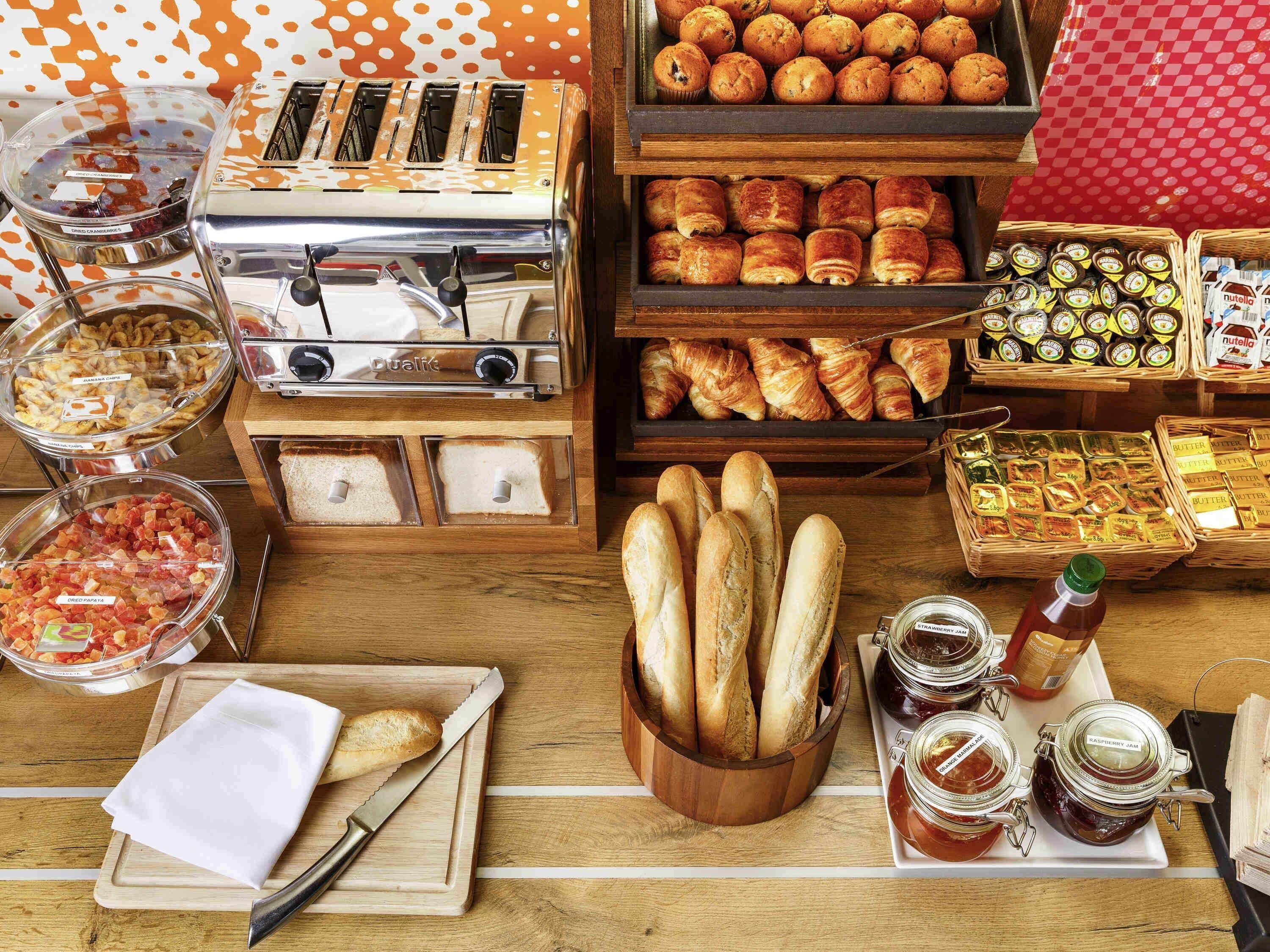 Un bufé de desayuno con diversas opciones de comida, como pastelería, pan y salsas.