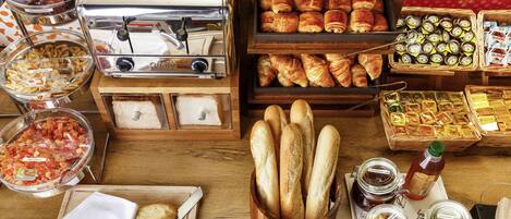 A breakfast buffet with various food items, including pastries, bread, and condiments.