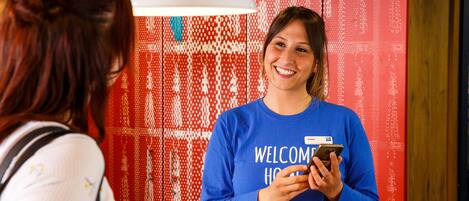 A person wearing a blue 'WELCOME HOME' sweatshirt holding a smartphone.