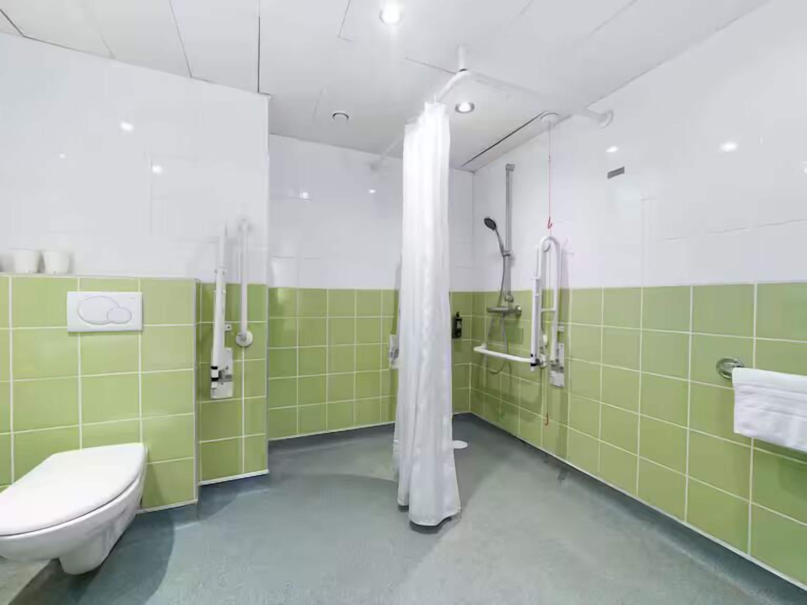 A bathroom with a toilet, a shower with a curtain, and a towel rack.