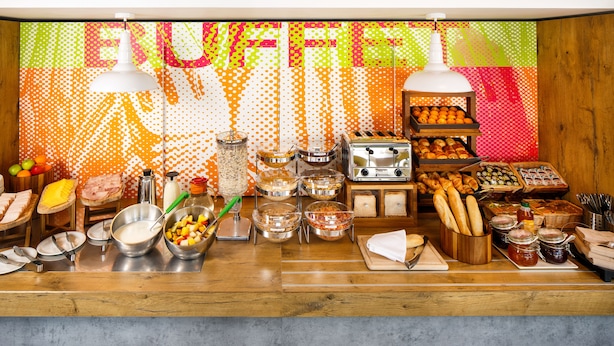 A buffet setup with various food items, utensils, and condiments. - ibis budget Southampton Centre (Southampton)