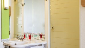 Un baño con lavamanos blanco, espejo y cabina de ducha de vidrio.