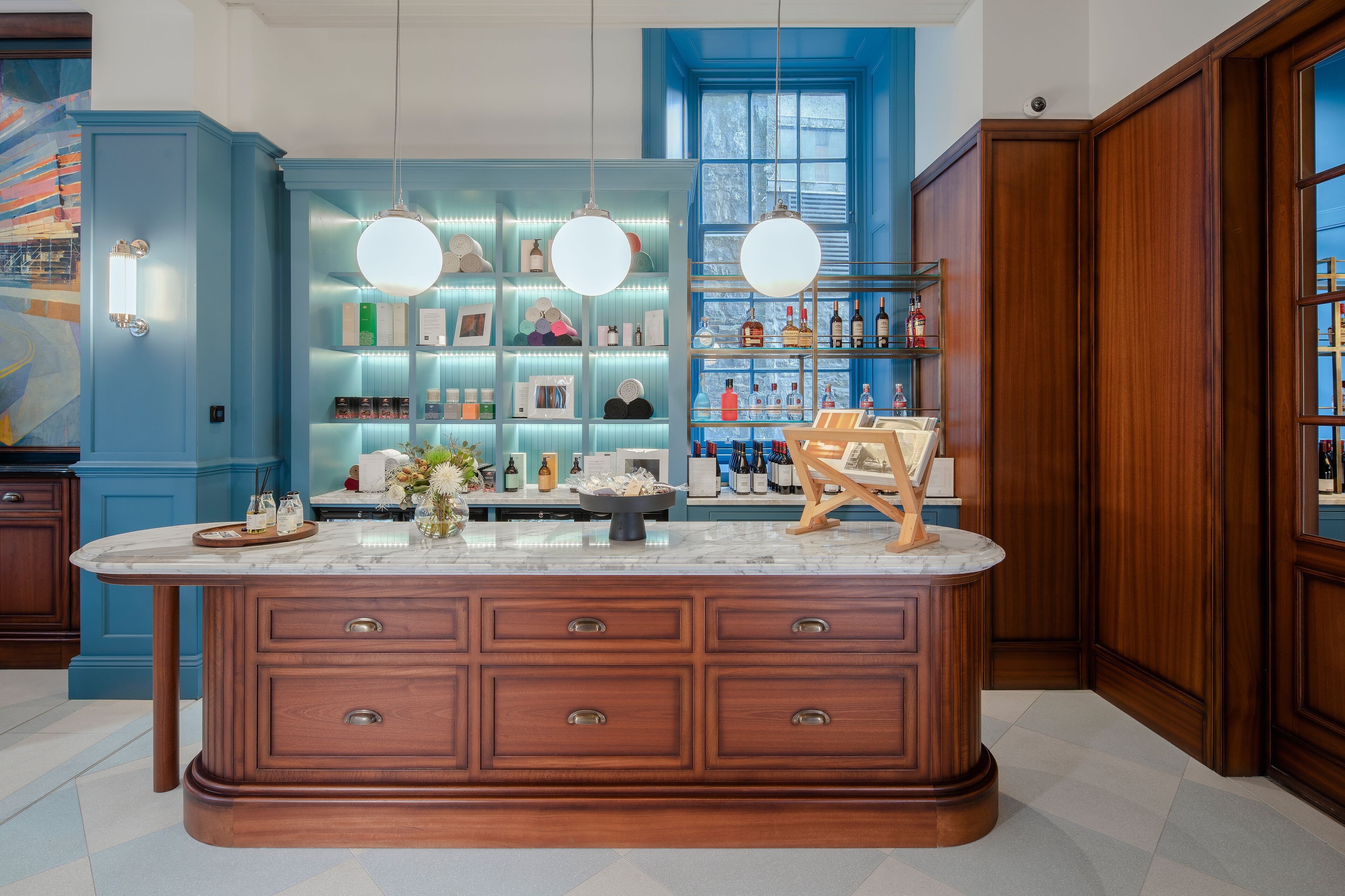 Une cuisine dotée d’un grand îlot central en marbre, de meubles en bois et d’un mur d’accent bleu.