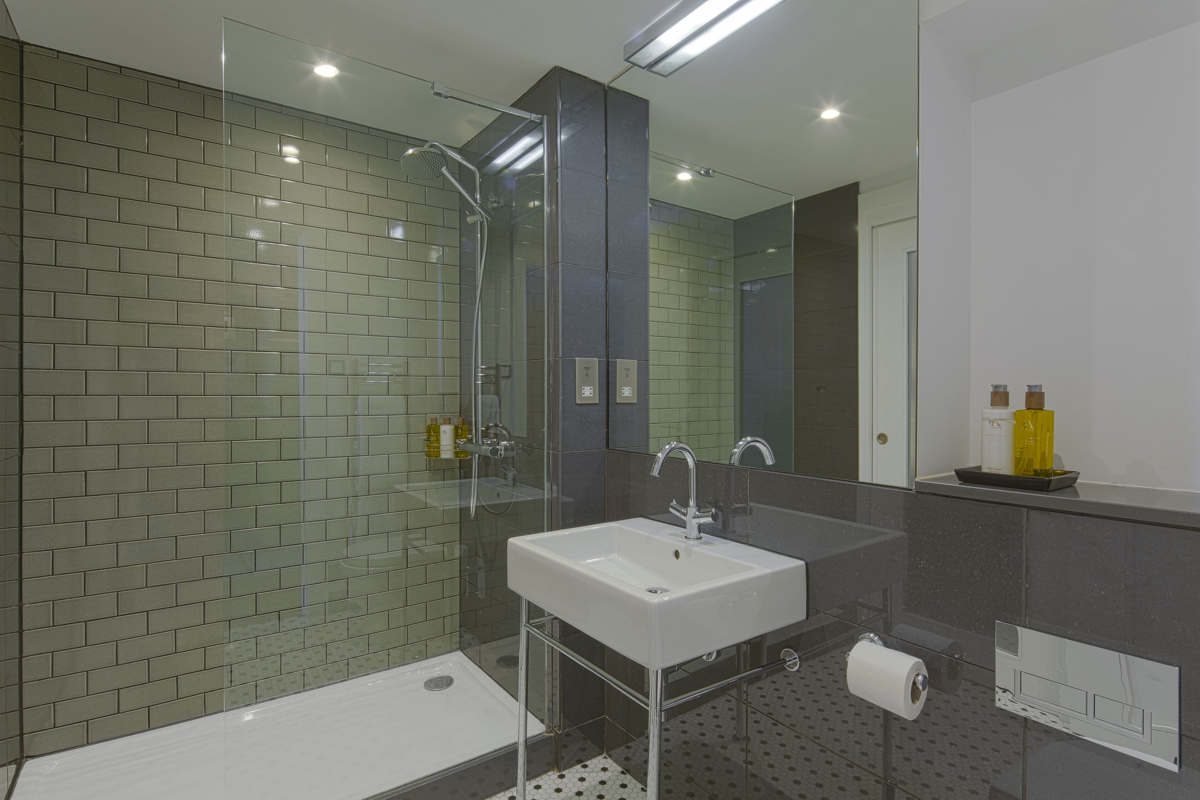 A modern bathroom with a glass shower enclosure, a white sink, and a mirror above it.