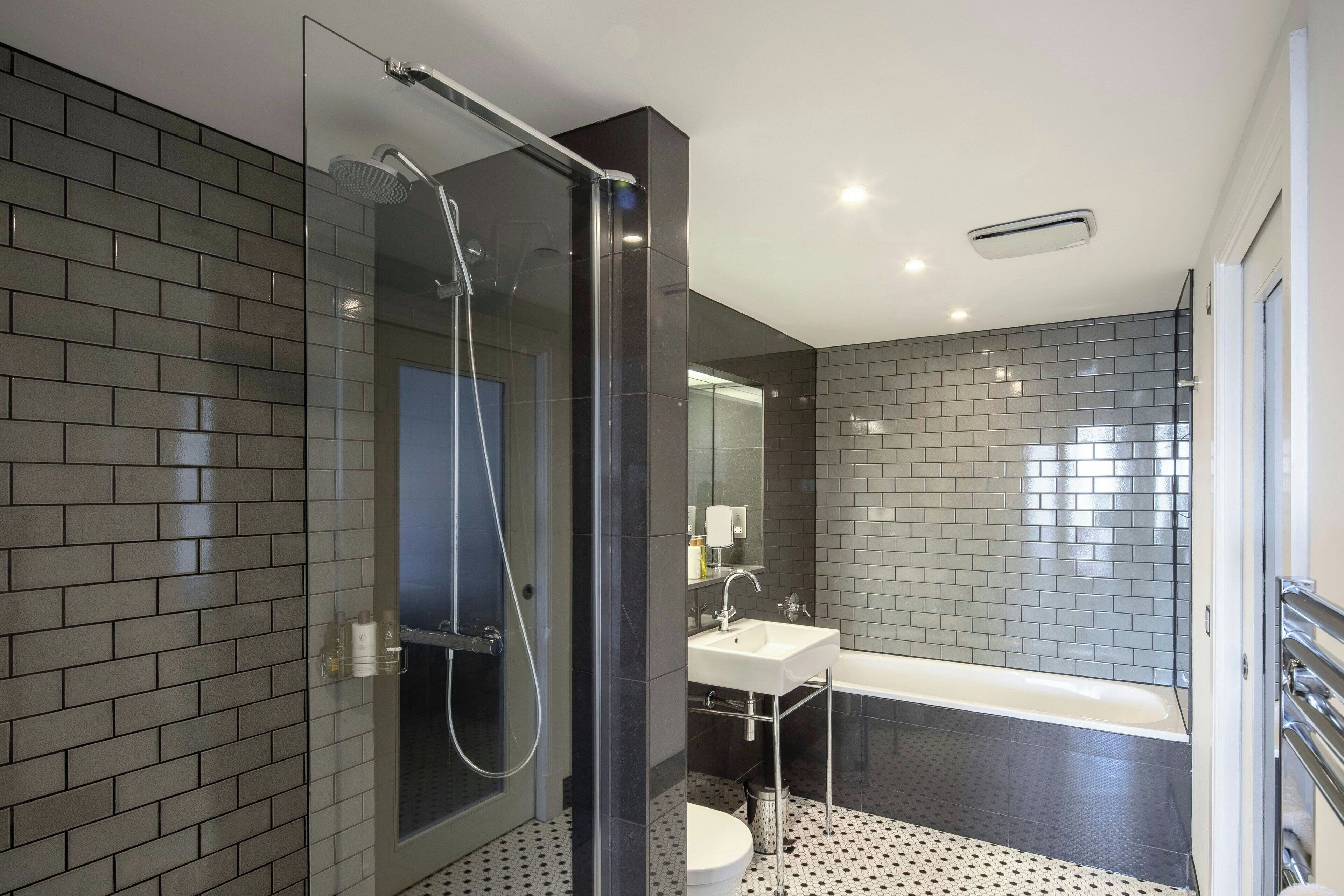 A modern bathroom with a glass-enclosed shower, a white sink, and a bathtub.