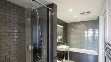 A modern bathroom with a glass-enclosed shower, a white sink, and a bathtub.