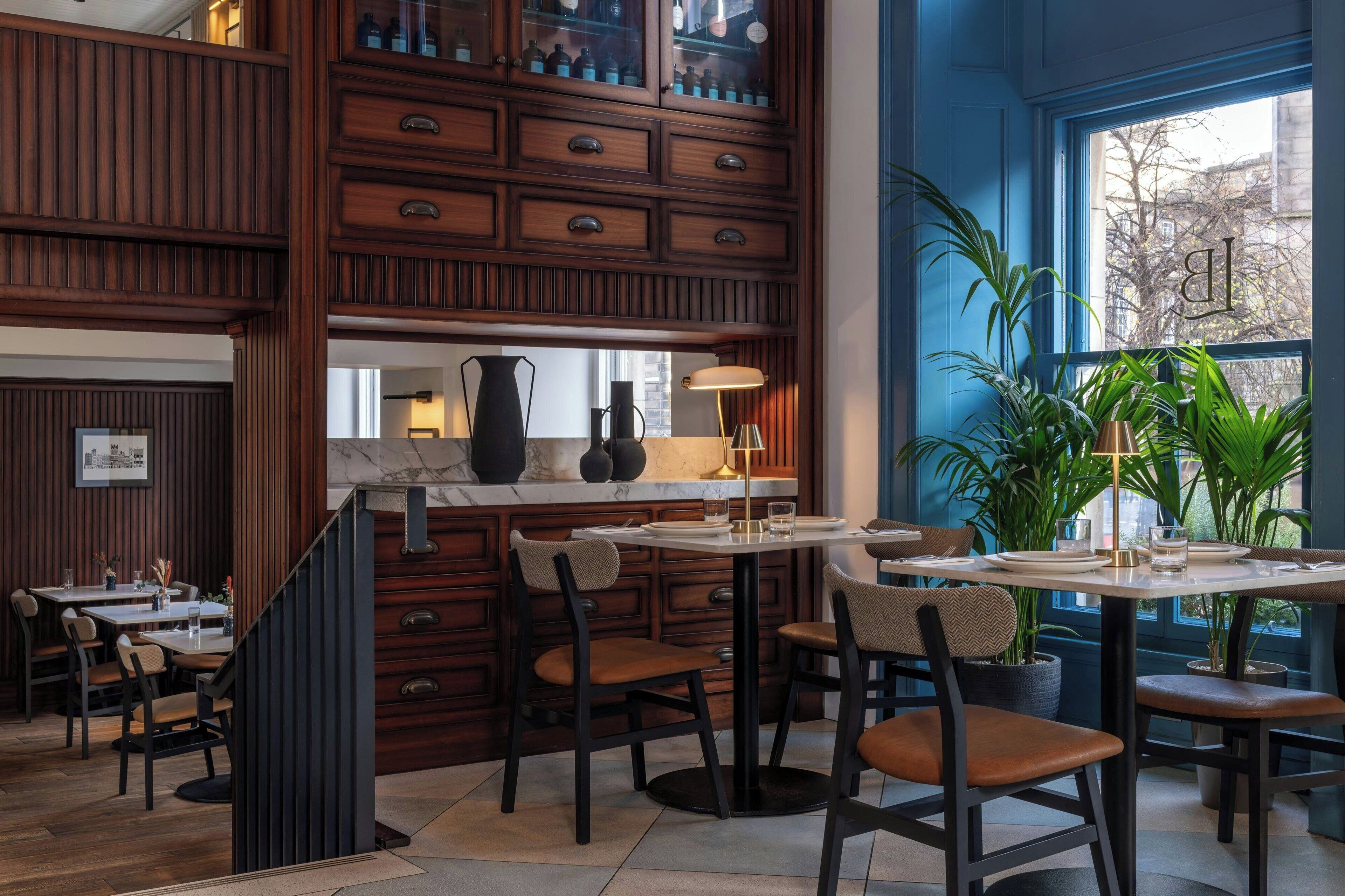 A restaurant with wooden paneling, a marble countertop, and multiple dining tables with chairs.
