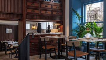 A restaurant with wooden paneling, a marble countertop, and multiple dining tables with chairs.