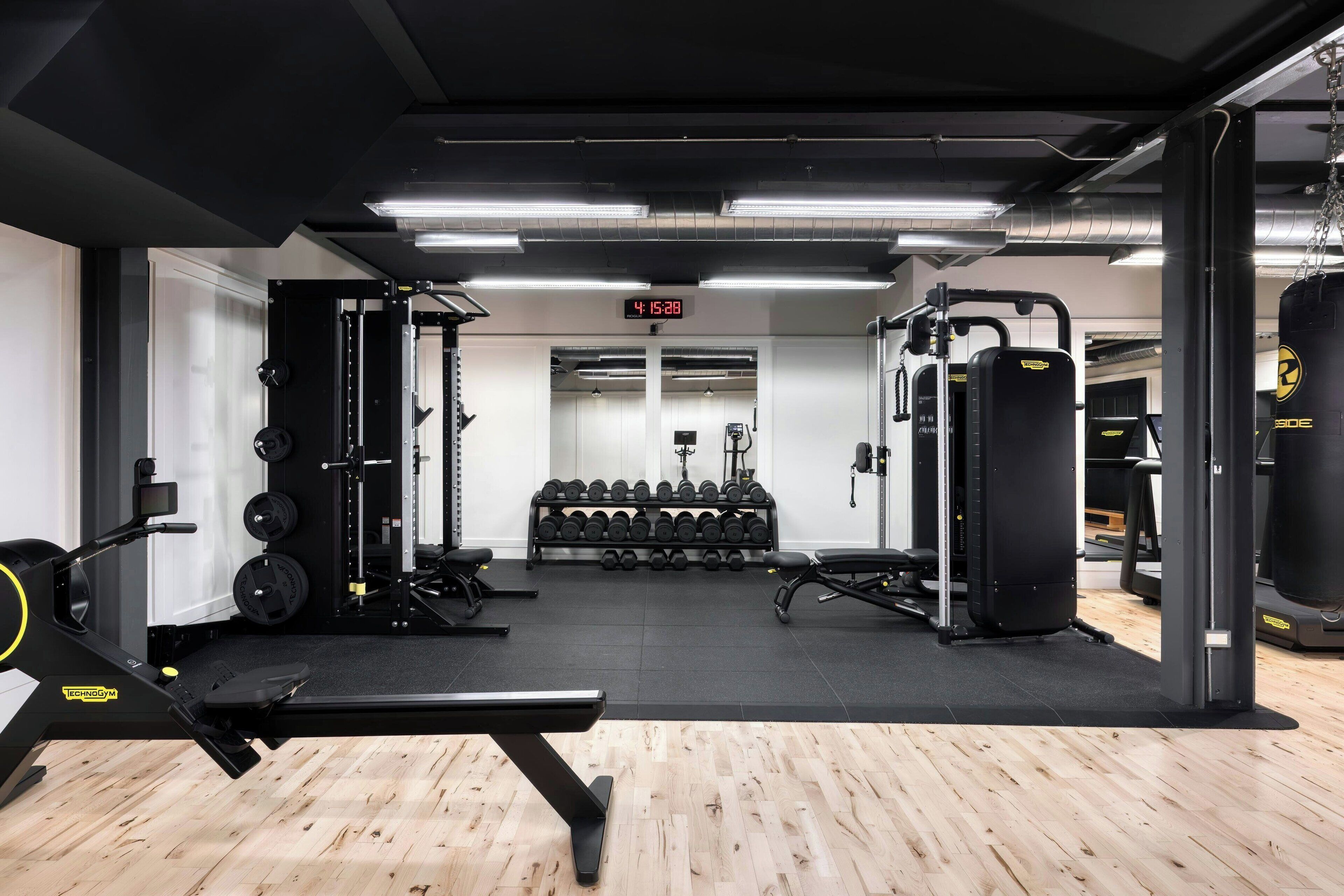 Un gimnasio con equipo de levantamiento de pesas, mancuernas y máquinas de cardio.