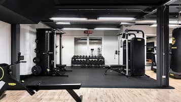 Un gimnasio con equipo de levantamiento de pesas, mancuernas y máquinas de cardio.