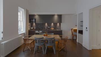 Una cocina moderna con armarios oscuros, una mesa de comedor de madera y dos sillas azules.
