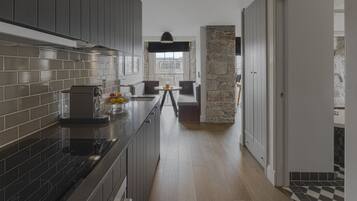 A modern kitchen with dark cabinetry, a black countertop, and a stone accent wall.