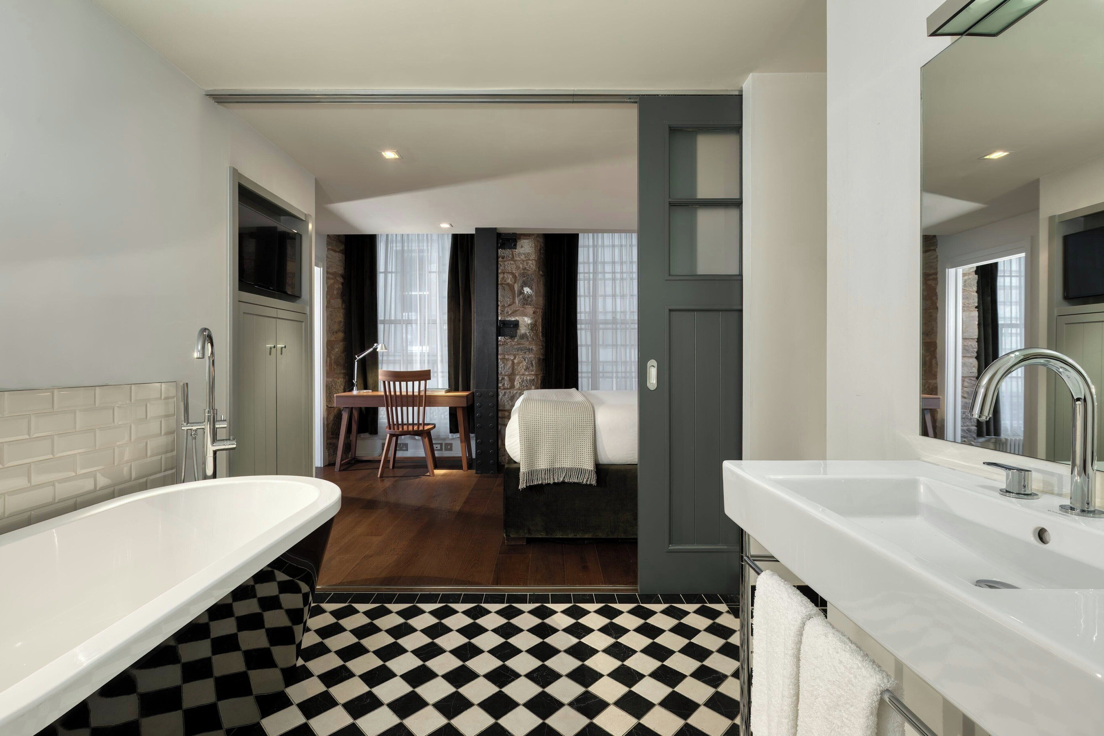 A modern bathroom with a large bathtub, a separate sink, and a checkered floor.