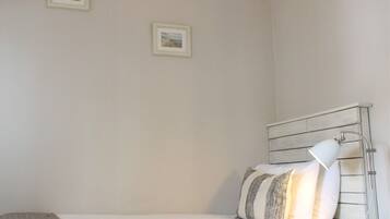 Un dormitorio con una cama, una lámpara de noche y dos cuadros en la pared.