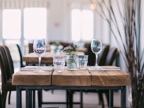 Una mesa de comedor dispuesta con copas de vino, vasos de agua y un pequeño jarrón con flores.