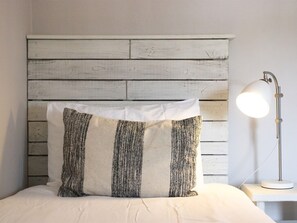 A bed with a white pillow and a headboard made of white wooden planks. - The Cliff House Hotel (New Milton)