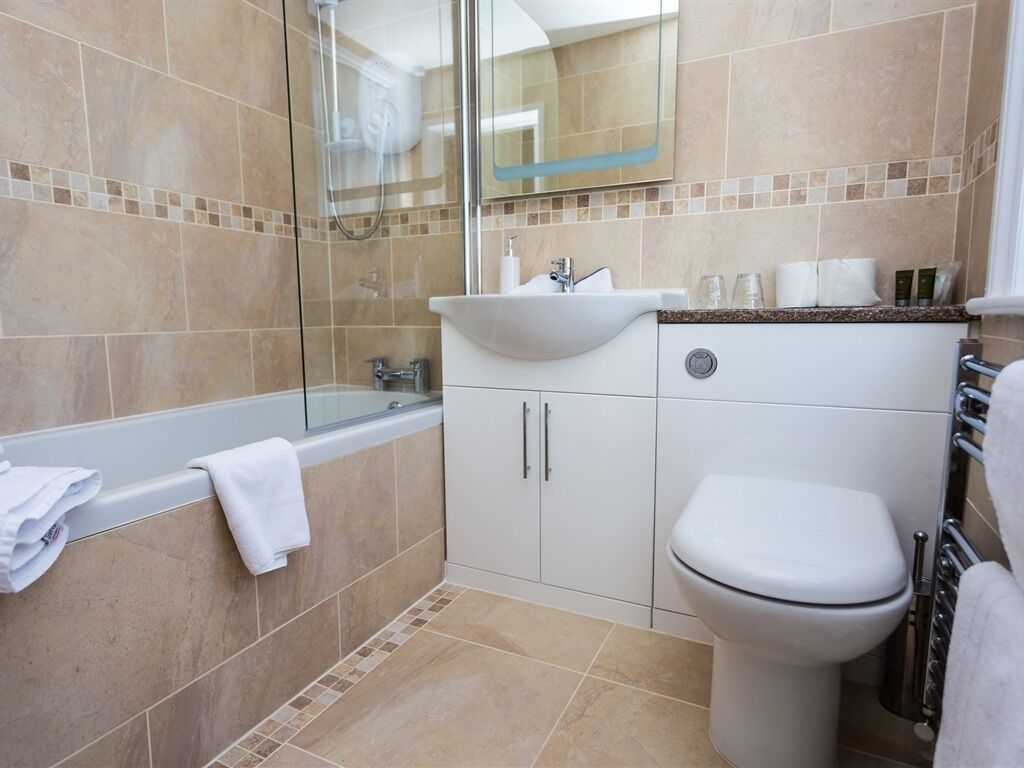 A modern bathroom with a glass shower enclosure, a white sink, and a toilet.