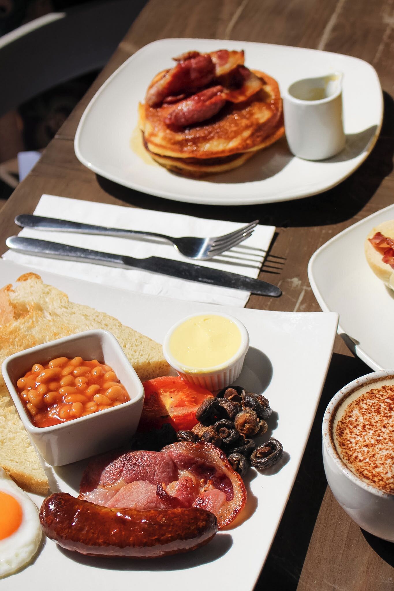 A breakfast plate with bacon, eggs, beans, and toast.