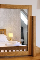 Una habitación de hotel con una cama, una lámpara de noche y un espejo que refleja el cuarto.