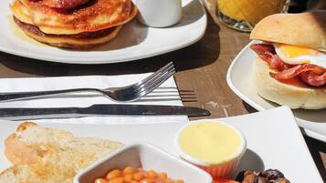 A breakfast setting with pancakes, eggs, toast, beans, and a glass of orange juice.