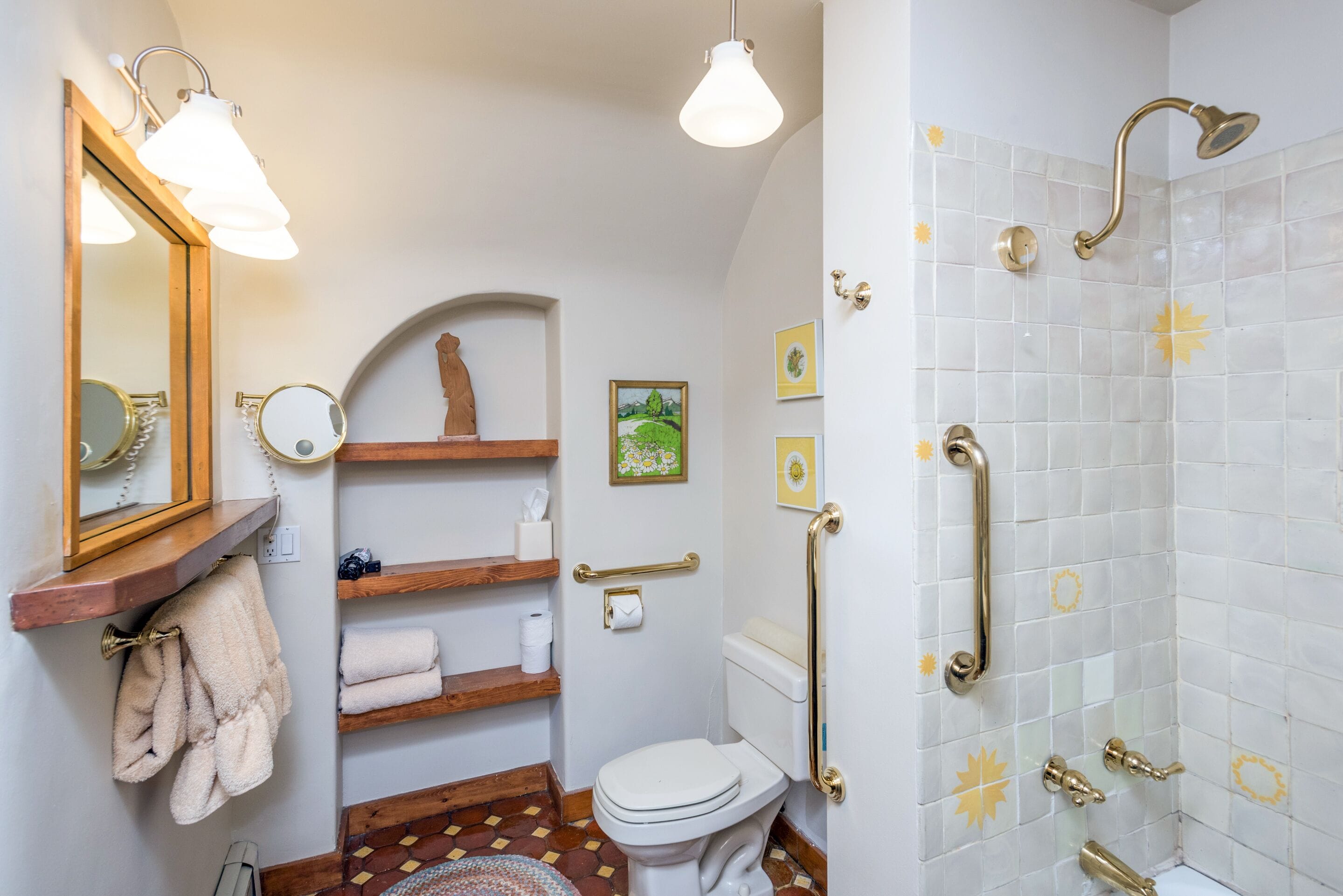 A bathroom with a toilet, sink, and shower. There are wooden shelves with towels and toiletries.