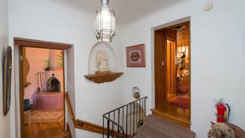 A staircase with a wooden handrail, a hanging lantern, and a small statue on the wall.