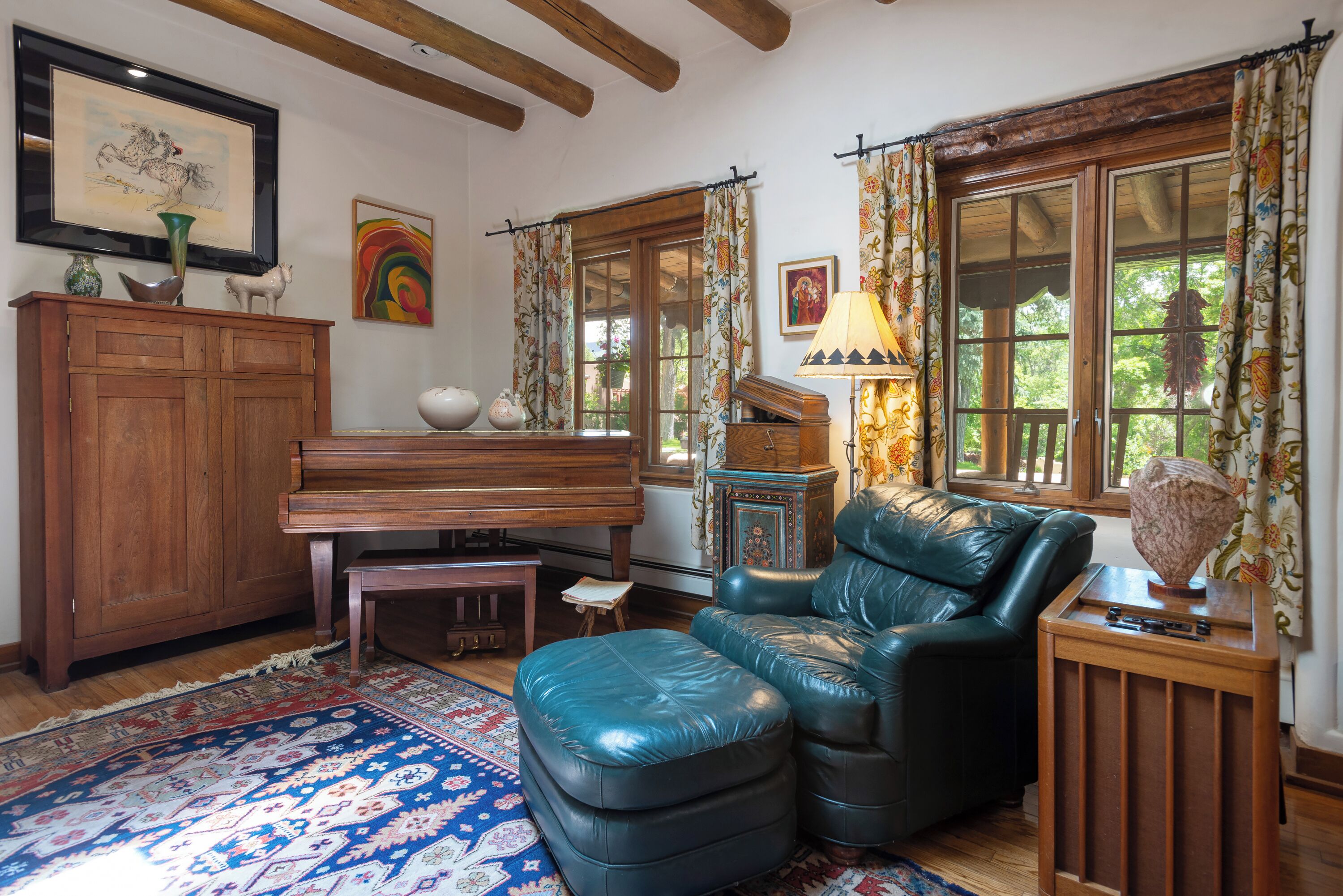 A cozy living room with a piano, leather armchair, and a patterned rug.