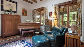 A cozy living room with a piano, leather armchair, and a patterned rug.