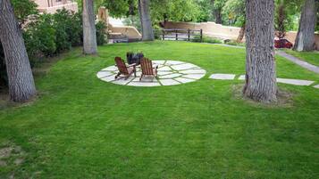 A well-maintained lawn with two Adirondack chairs and a circular stone pattern.