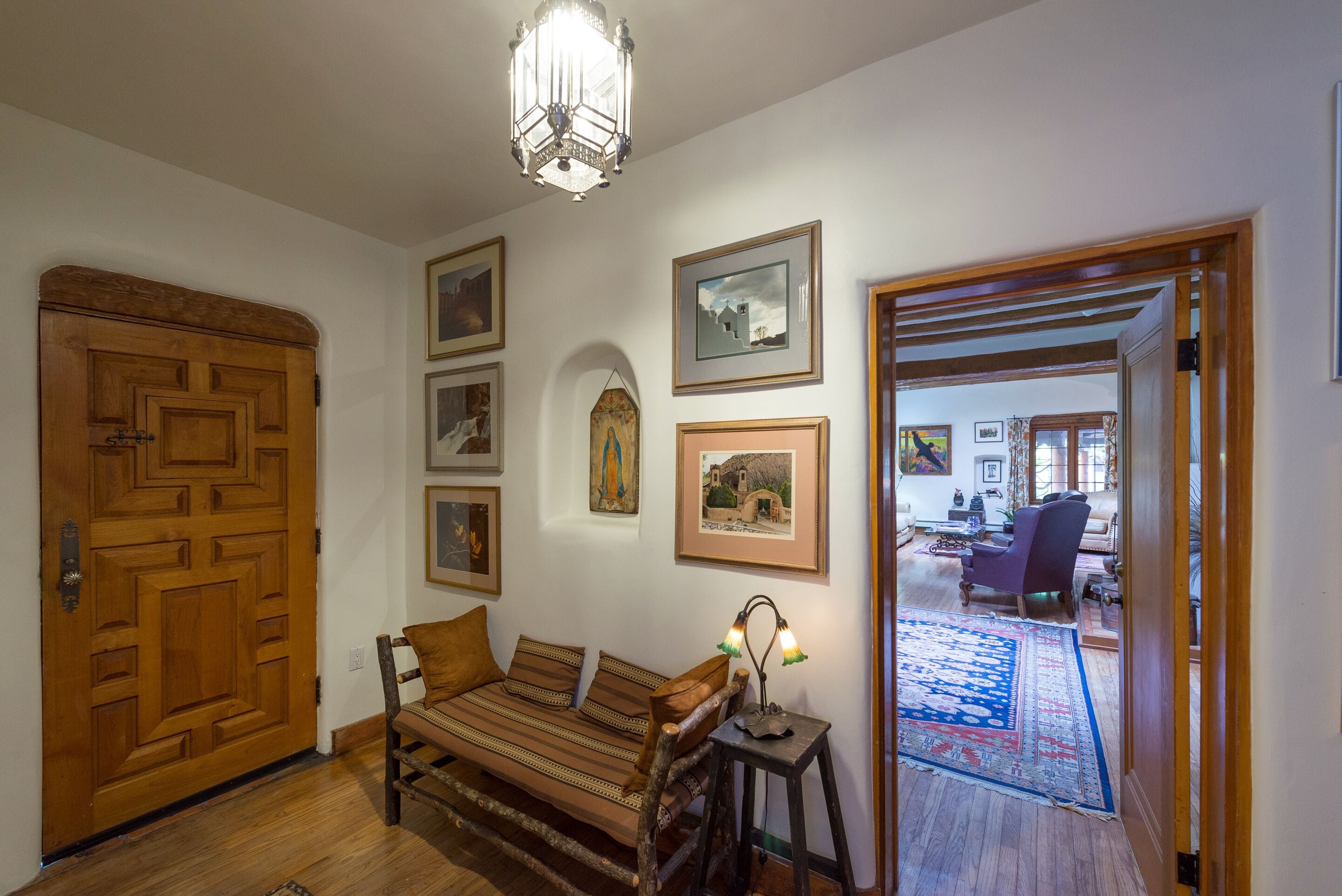 Un salon chaleureux avec un canapé en bois, une petite table avec une lampe et une grande porte en bois.