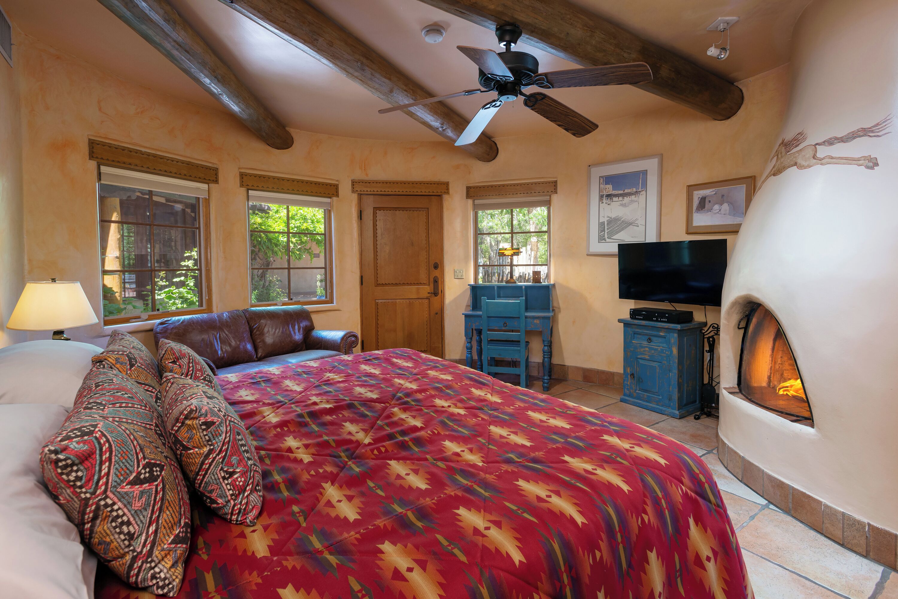 Un dormitorio con una cama, chimenea, televisión y escritorio.