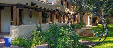 A rustic building with a porch, hanging plants, and a swing.