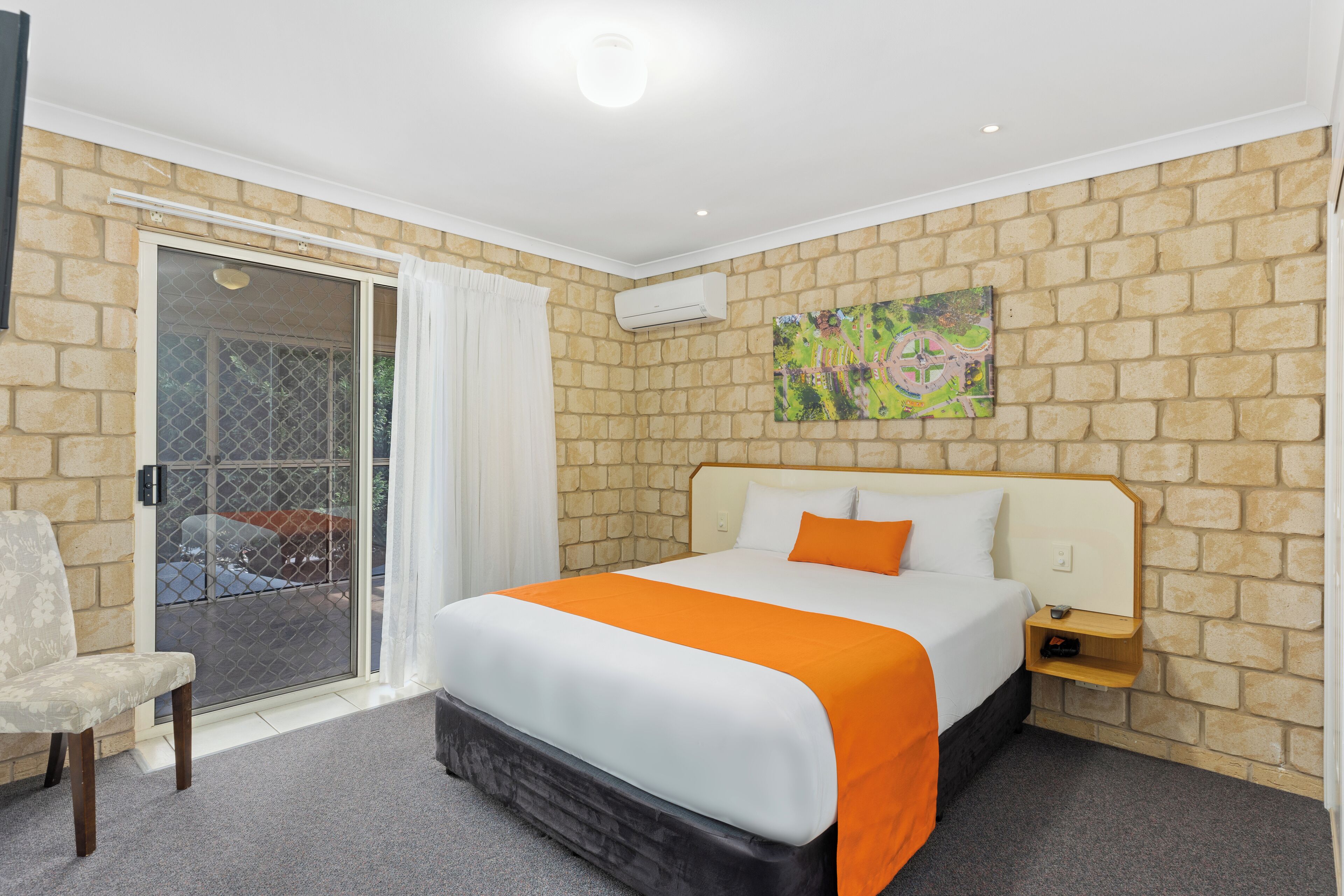 A hotel room with a large bed, a chair, a small table, and a window with a view.