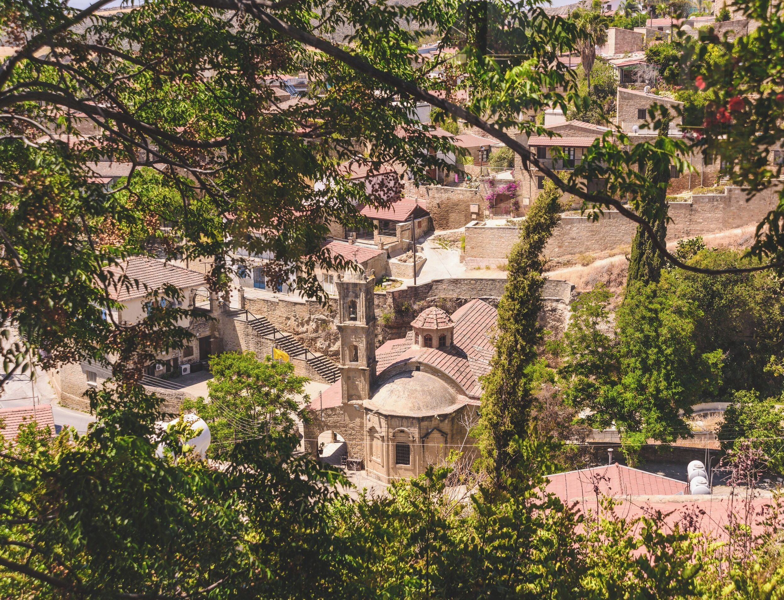 Un pueblo histórico con edificios de piedra, una iglesia destacada con campanario, y una combinación de edificaciones residenciales y comerciales.