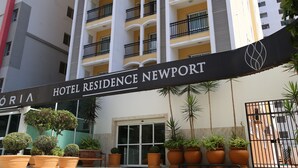 L’entrée d’un hôtel, avec une enseigne indiquant « HÔTEL RÉSIDENCE NEWPORT » et des plantes en pot devant.