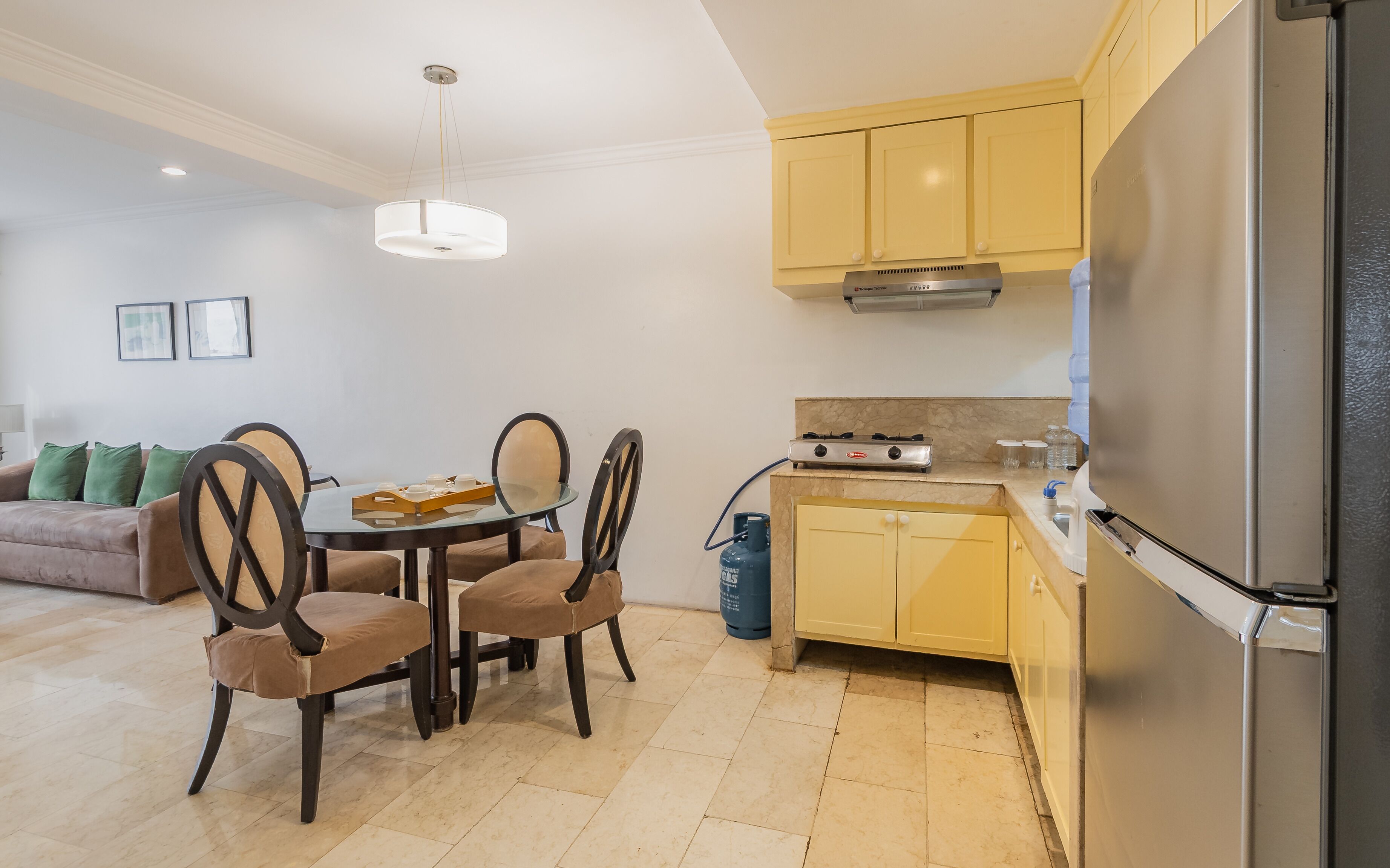 A modern kitchen with a gas stove, a refrigerator, and a dining area with a table and chairs.