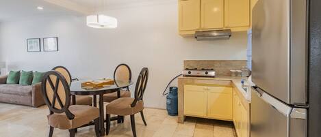 A modern kitchen with a gas stove, a refrigerator, and a dining area with a table and chairs.