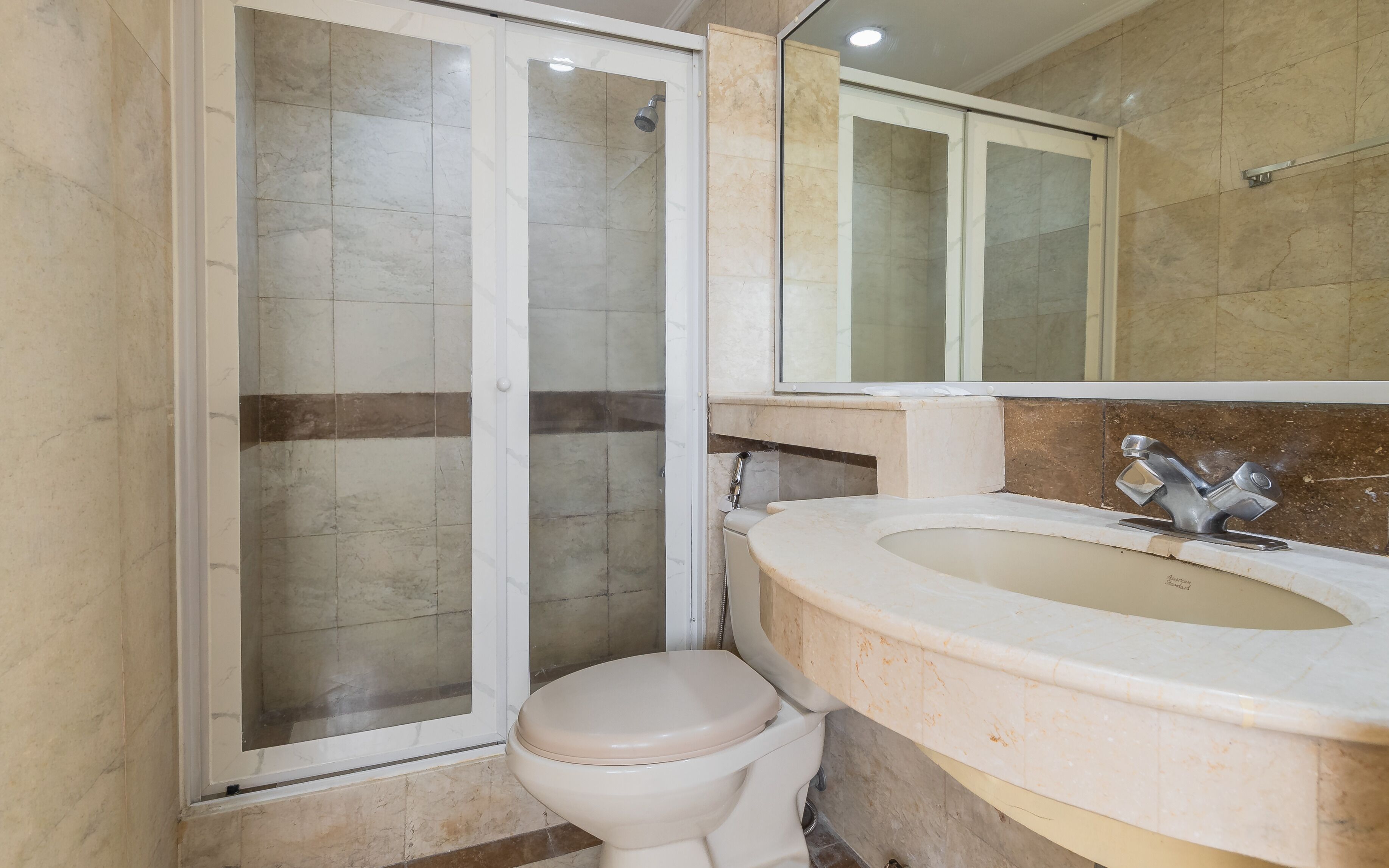 Un baño con inodoro, lavamanos y cabina de ducha.