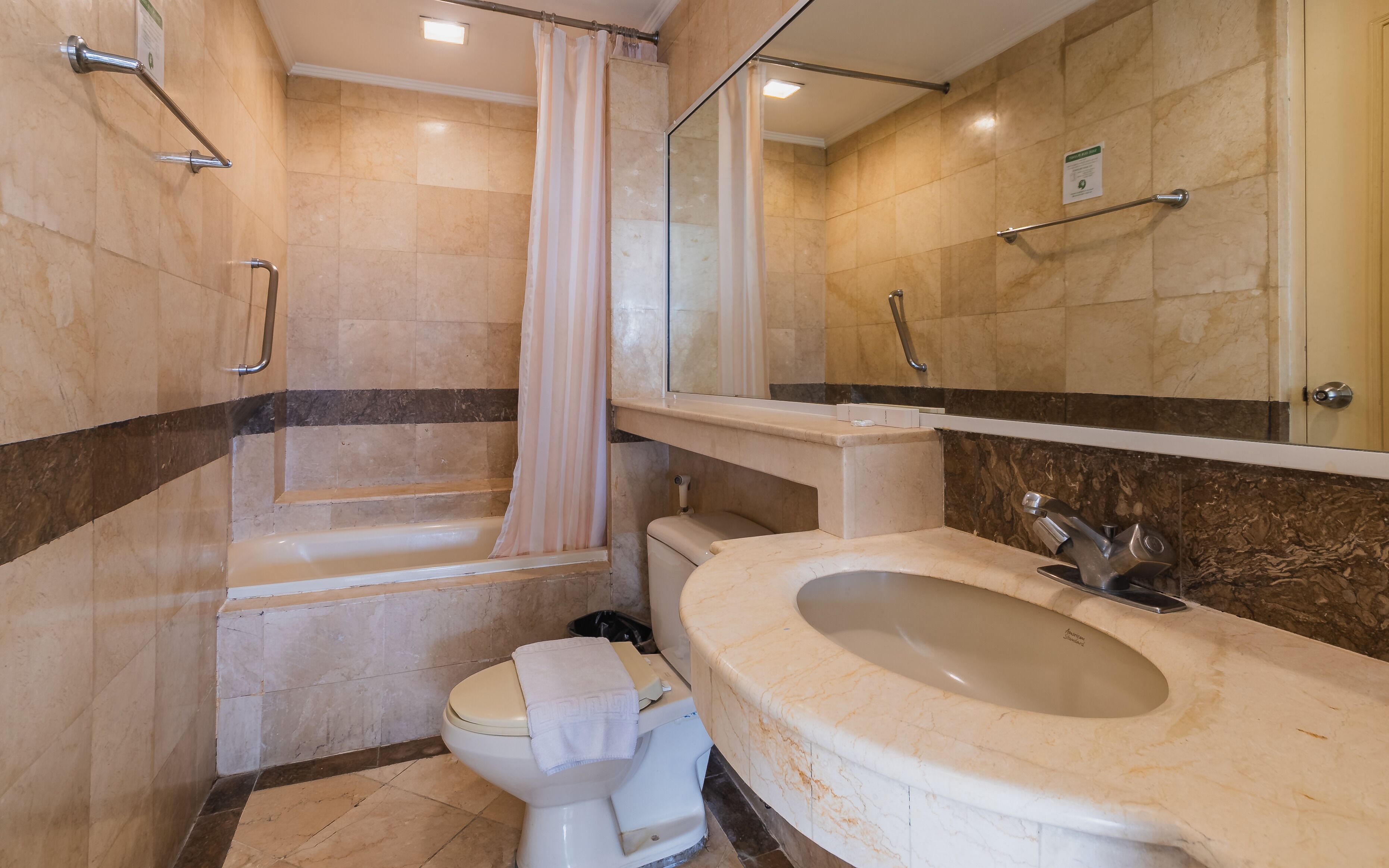 A bathroom with a bathtub, toilet, sink, and a mirror.