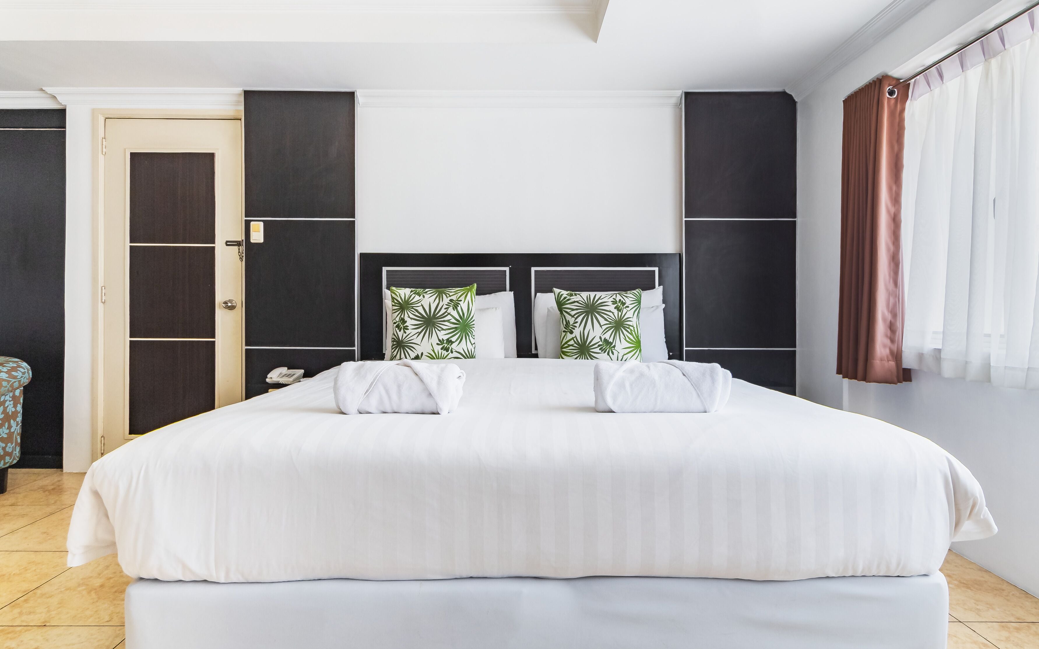 A modern hotel room with a large bed, a wardrobe, and a bathroom door.