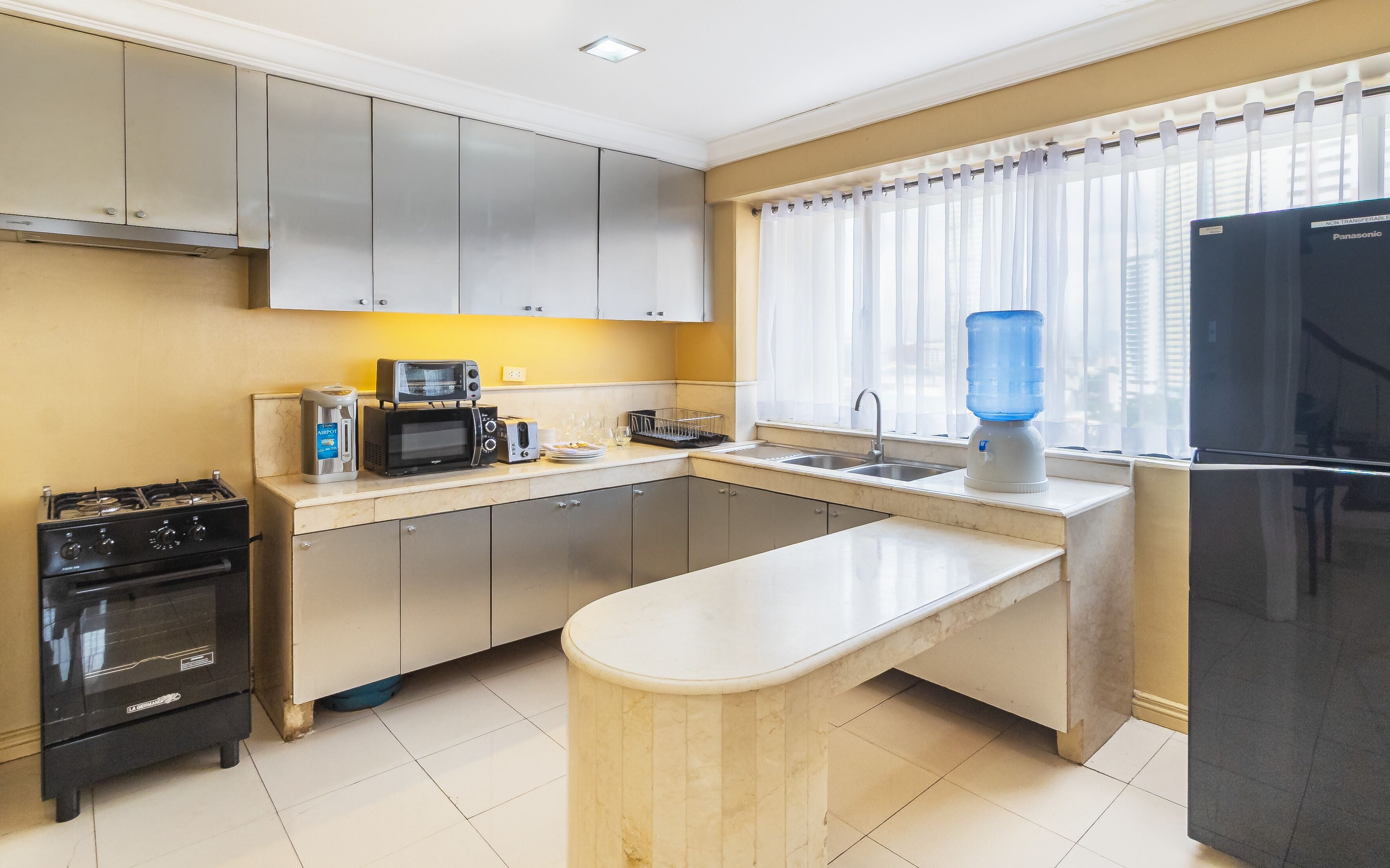 A compact kitchen with a gas stove, a microwave, a toaster, a sink, and a refrigerator.
