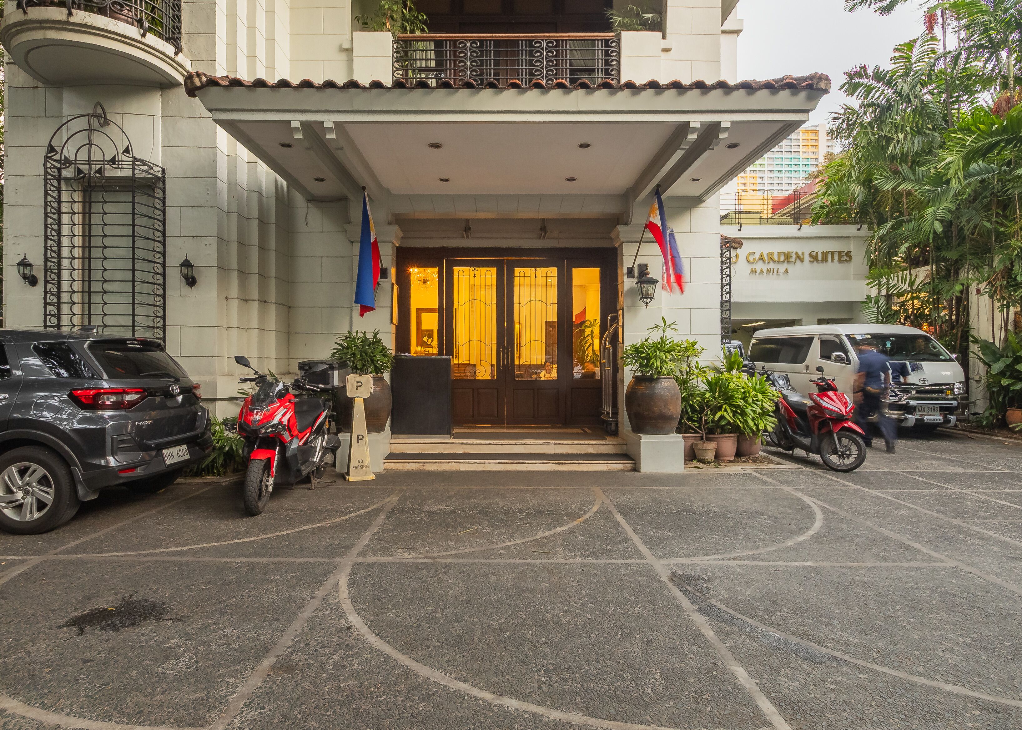 A hotel entrance with a dark wooden door, a parking area, and a sign indicating no parking.