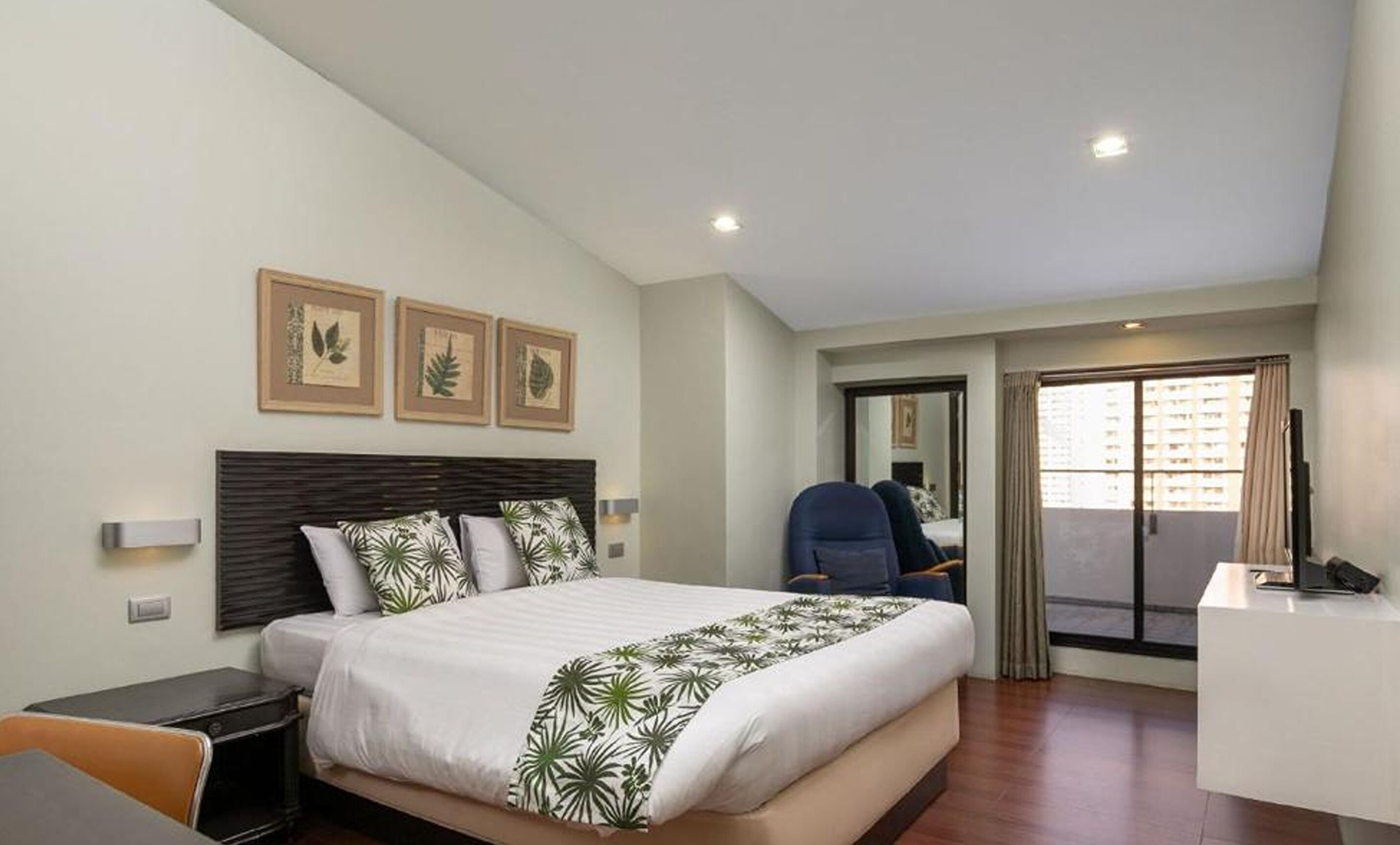 Ein Hotelzimmer mit Bett, Schreibtisch, Stuhl und einem Balkon mit Blick.